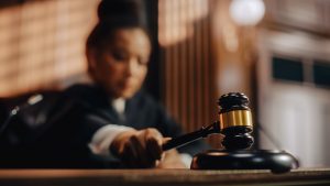 Courtroom scene with an honourable female judge striking a gavel to pronounce a sentence, close-up on the judge’s mallet.